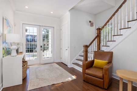 Step into your elegant entryway with gleaming hardwood floors, cozy leather seating, and French doors opening to your private outdoor space.