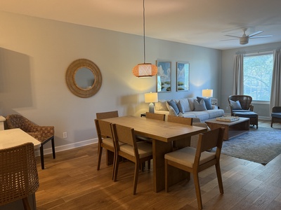 Gather around your elegant dining table while cozy seating awaits nearby, all bathed in warm light from stylish fixtures.