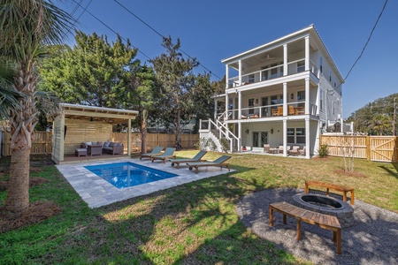 Modern three-story beach house with private pool, fire pit, and covered outdoor lounge area surrounded by tropical landscaping.