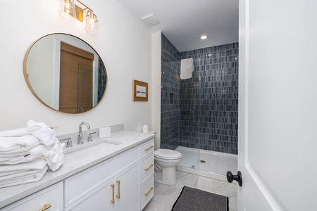 Step into your beautifully appointed bathroom featuring a stunning tiled shower, elegant vanity, and thoughtful touches like fluffy towels.