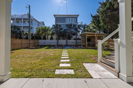 Step onto your private lawn area with charming walkway stones leading through the green space to outdoor seating.