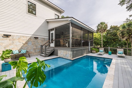 Sparkling private pool with a screened porch and stone accents, offering a serene space to relax after a day at the beach
