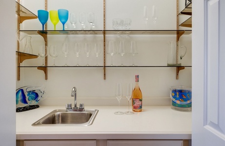 A built-in wet bar with sinks and open shelving for drinks and glassware