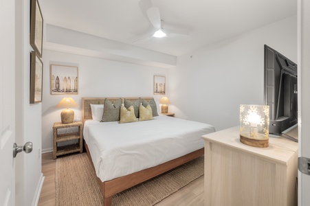 Your peaceful bedroom sanctuary features crisp white linens, warm wood tones, and soft coastal-inspired decor that invites deep, restful sleep.