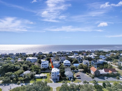Aerial view of a charming coastal neighborhood with vacation homes nestled among trees, just steps from the pristine beach.