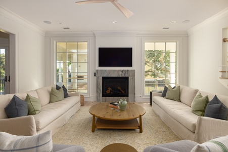 Sink into plush sofas by the marble fireplace, where natural light streams through French doors onto your peaceful retreat.