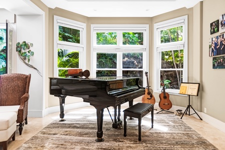 Bright music room with piano and garden-view bay windows.