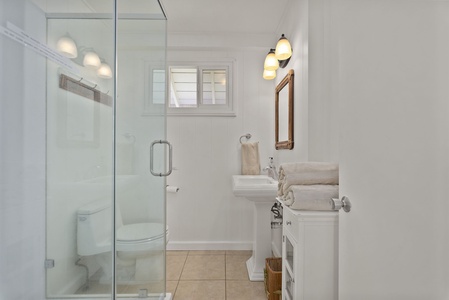 Step into your bright, modern bathroom featuring a spacious glass shower and pristine white vanity with fresh towels awaiting your arrival.