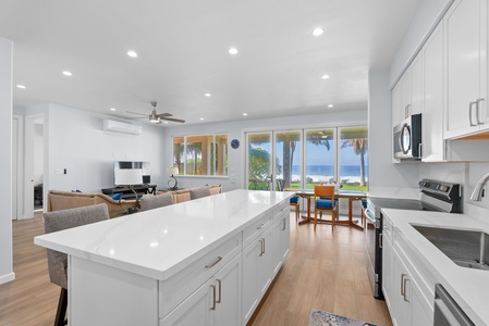 Panoramic prep space with island counter and ocean views extending through the home.