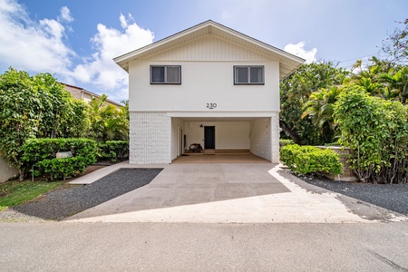 Front view of the home featuring a spacious driveway and lush tropical greenery, welcoming you to your Hawaiian retreat.