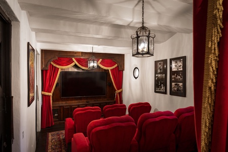 Your private theater awaits with plush red velvet seating and elegant draping for cozy movie nights.
