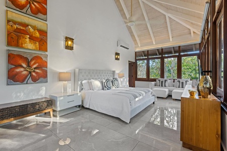 The spacious guest bedroom with plush bed, a comfortable seating area and serene view.
