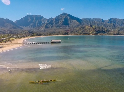 Pristine bay with dramatic mountain backdrop, sandy beach, and crystal-clear waters perfect for kayaking and seaside relaxation.