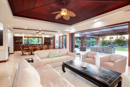 Spacious open-plan living room with vaulted ceilings, elegant wood accents, and seamless outdoor access.