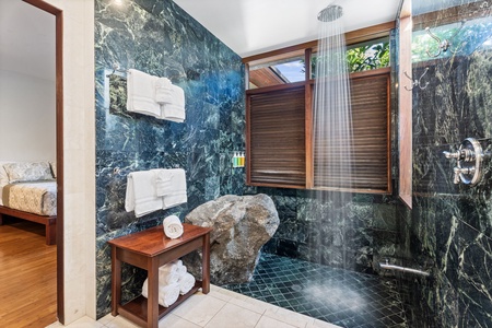 Your spa-inspired bathroom features stunning marble walls and an oversized rainfall shower with natural stone accents for ultimate relaxation.