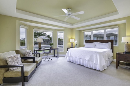 The spacious Primary bedroom features a plush King size bed, a dedicated workspace area nestled up to the bay windows, and walk in closet.
