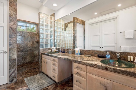 Primary bathroom with double vanity and walk-in glass block shower.