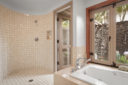 Unwind in the spa-inspired bathroom featuring a walk-in shower, deep soaking tub, and tranquil garden views.