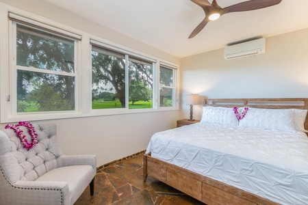 Guest bedroom at Pohaku Villa with a king bed, natural light, and views of the surrounding tropical landscape.