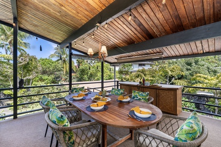 Your covered terrace invites tropical dining with warm wood beams overhead and lush garden views stretching beyond the table.
