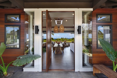 Grand pivot doors open to a stunning indoor-outdoor living space with ocean views.