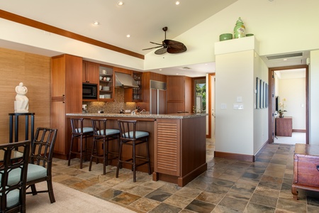 Gleaming modern kitchen with bar seating and top tier appliances.