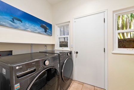 Your dedicated laundry room keeps vacation clothes fresh with modern washer and dryer, plus cheerful ocean artwork brightening your daily routine.