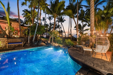 Slip into your private tropical paradise with a stunning heated pool surrounded by swaying palms and stylish seating at twilight.