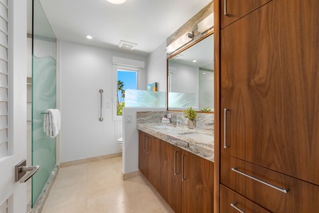 Modern ensuite with double sinks, a glass walk-in shower, and rich wood cabinetry to elevate your morning routine.
