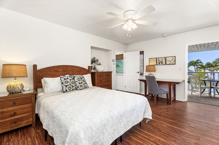 Your tropical bedroom awaits with warm wood floors, carved headboard, and private lanai access for morning coffee with palm tree views.