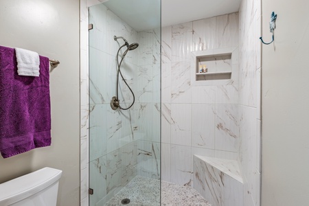 Relax in Maui Kaanapali Villas 292’s marble-accented shower with bench and glass half door.