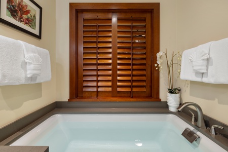 Sink into your private soaking tub surrounded by warm wood shutters and crisp white linens—your perfect retreat awaits.