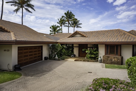 Elegant tropical property with circular driveway, lush landscaping, and swaying palm trees creating a peaceful island retreat atmosphere.