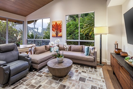 Relax in the cozy media lounge with plush recliners and smart TV, framed by tropical scenery.