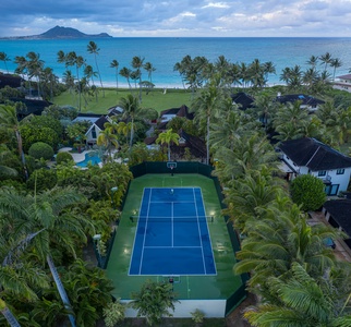 Aerial view of the tennis court surrounded by lush tropical landscaping.