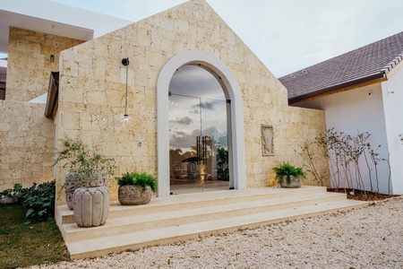 Elegant stone exterior with a large arched doorway leading to the beautiful villa..