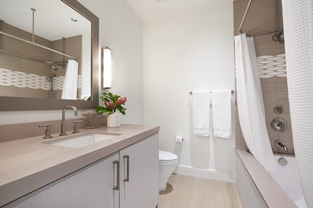 Elegant en suite bathroom with a modern vanity, bright lighting, and a relaxing soaking tub.