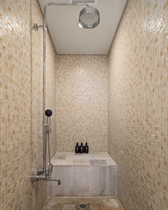 Elegant tiled shower with a built-in bench and rainfall showerhead.