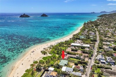 Aerial view highlighting the prime beachfront location, nestled among lush greenery with clear blue waters just steps away.