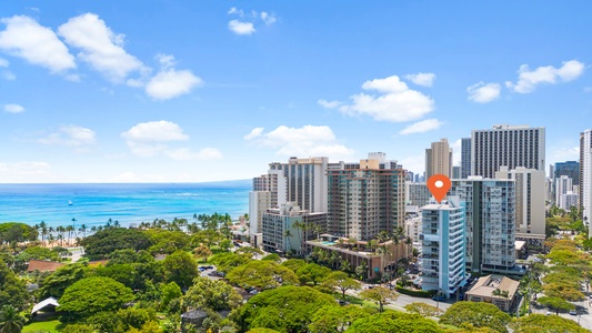 Panoramic view of a vibrant neighborhood with modern high-rise buildings set against a backdrop of the ocean and lush greenery.