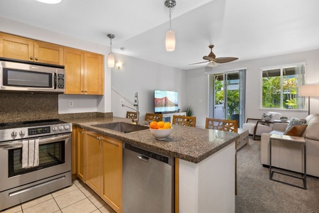 A fully-stocked kitchen features an island bar for quick meals and stainless steel appliances