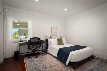 Recharge in this quiet bedroom with a workspace, soft linens, and warm natural light.