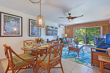 The open-concept dining and living area features tropical-inspired décor, comfortable seating, and access to the lanai with beautiful ocean views.