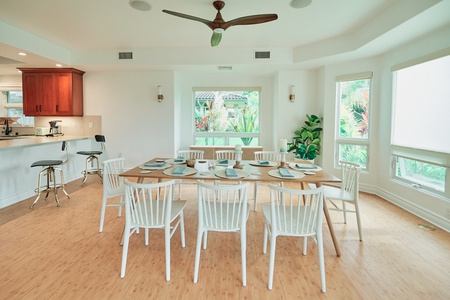 Gather your group around this beautiful dining table where natural light streams through large windows overlooking lush tropical greenery.