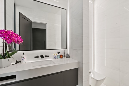 The stylish powder room features modern textures and ambient lighting—perfect for guest use during gatherings.