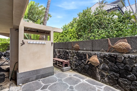 Private outdoor shower with stone flooring and lush greenery—rinse off post-beach in pure island style.