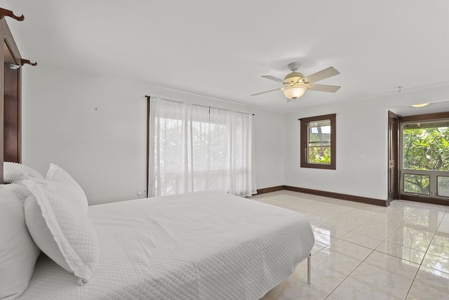 Bright guest bedroom with ceiling fan and private outdoor access.