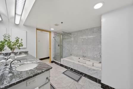 Refresh in the marble-clad bathroom with a soaking tub and glass walk-in shower.