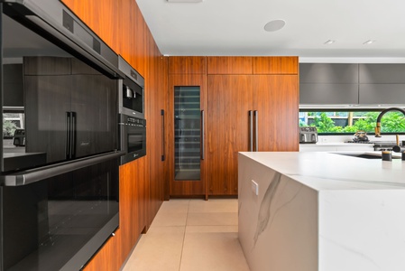 Sleek, wood-accented cabinetry blends with modern technology—note the wine fridge for your favorite vintage pairings.