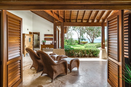 Enjoy the open-air living space with comfortable seating, offering seamless access to the lush garden and ocean views.